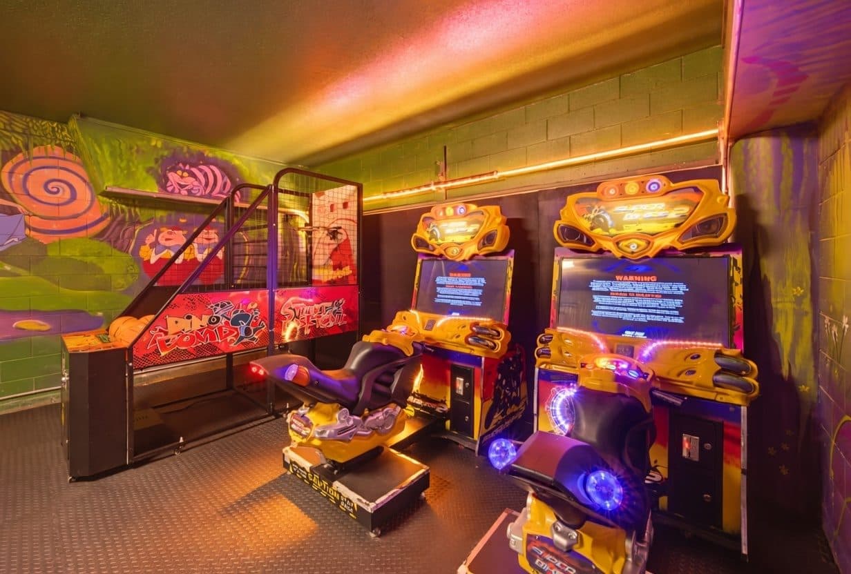 Candy themed arcade and games room with racing cabinets and LED cove lighting at a Davenport vacation rental