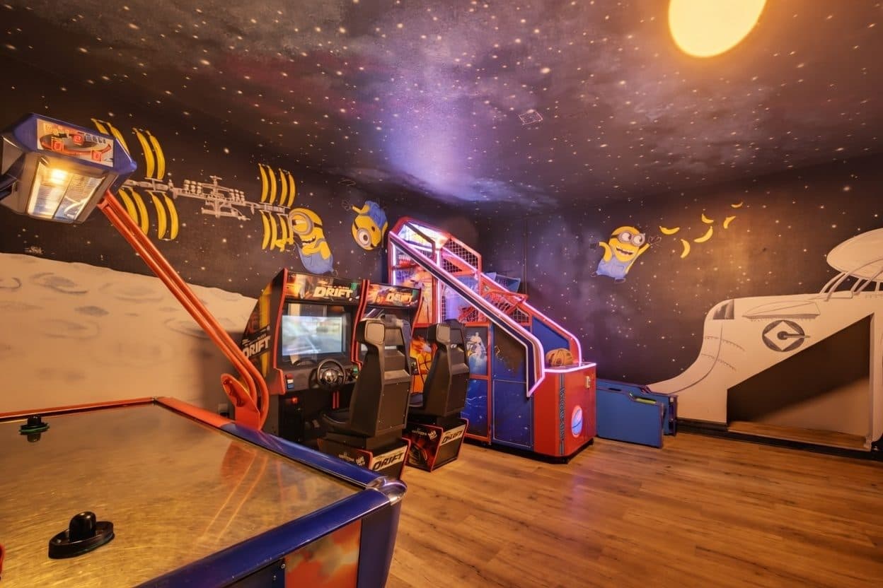 Neon lit arcade and games room with basketball machine and racing cabinets at a Kissimmee vacation rental