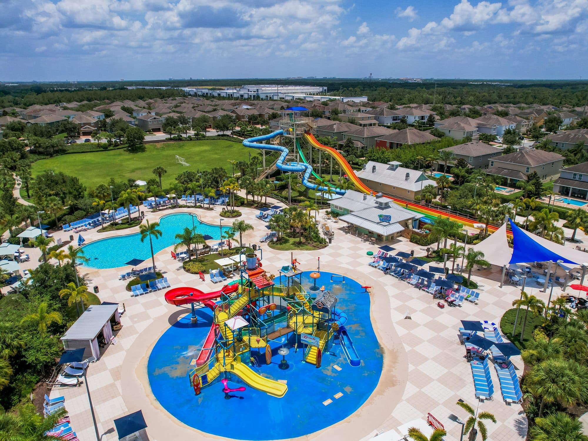 Drone aerial of a resort community water park with slides and zero-entry pool serving Orlando area vacation rentals